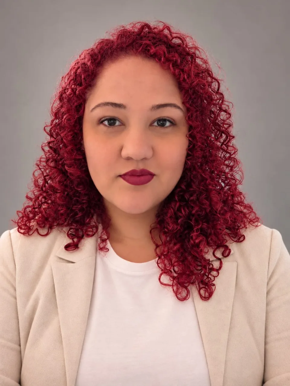 Retrato profissional de Barbara, com cabelos cacheados avermelhados e blazer claro